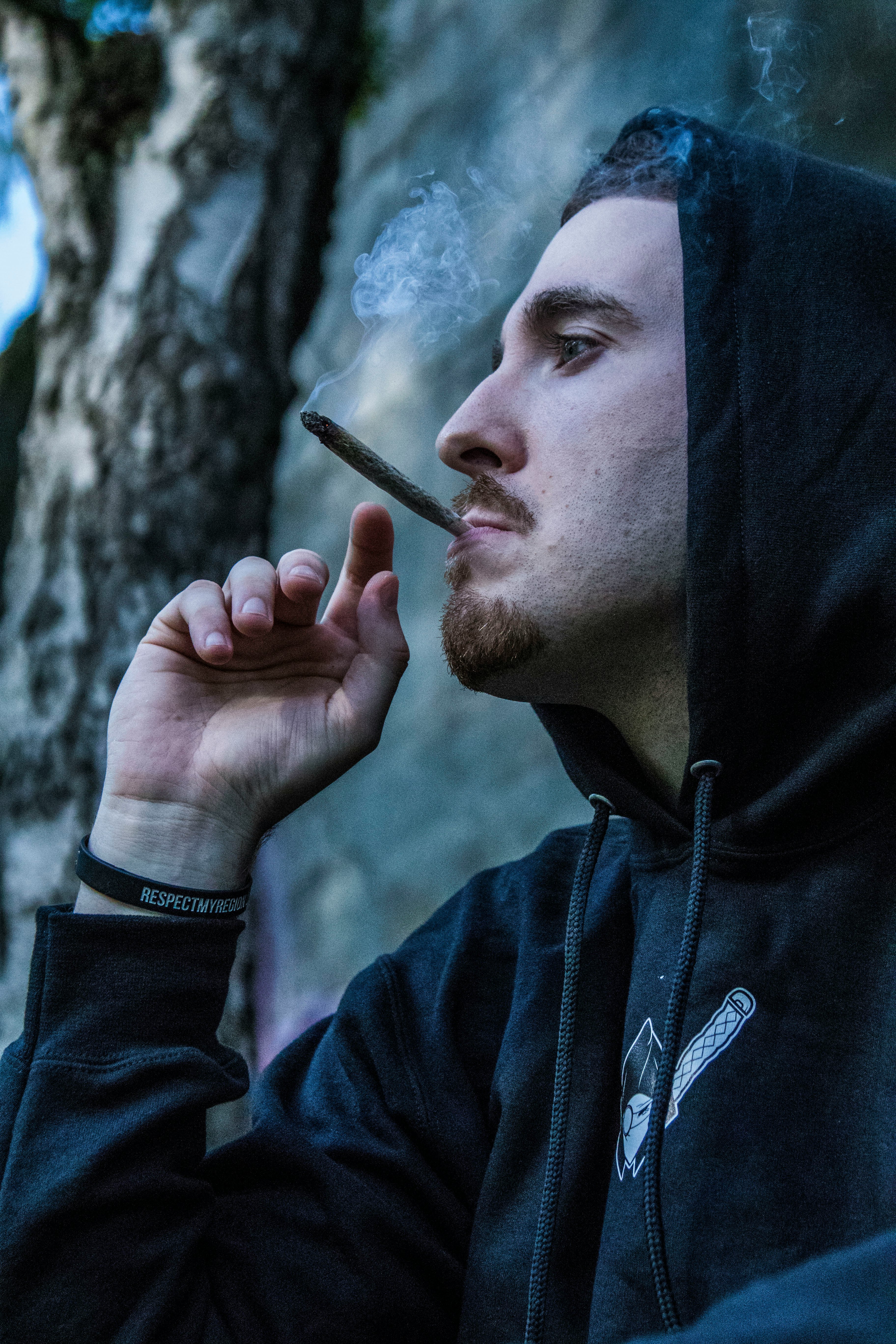 man in black hoodie using brown joint